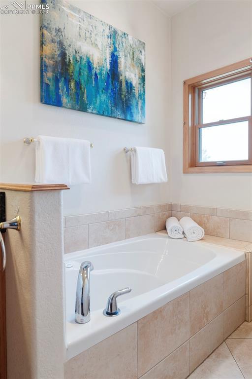 bathroom featuring a relaxing tiled tub and tile patterned flooring