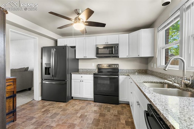 kitchen with light stone countertops, ceiling fan, black appliances, sink, and white cabinets