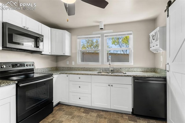 kitchen with stainless steel appliances, white cabinets, a barn door, sink, and ceiling fan