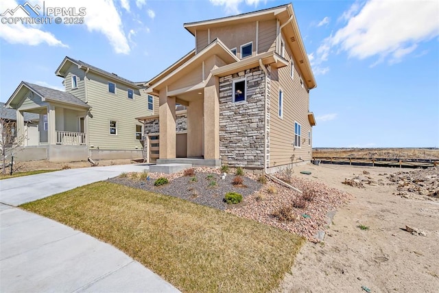 view of front of property featuring concrete driveway, fence, a porch, and stone siding