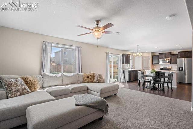 living room with dark hardwood / wood-style flooring and ceiling fan with notable chandelier