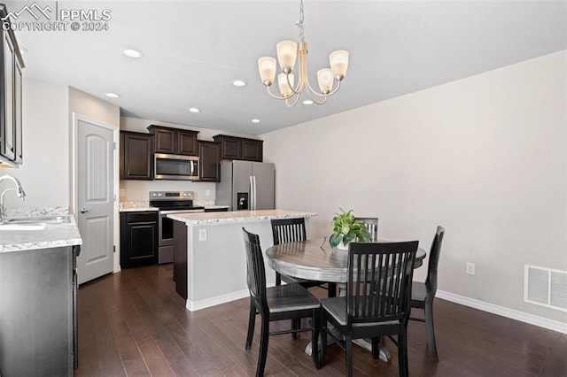 dining space with dark hardwood / wood-style floors, sink, and an inviting chandelier