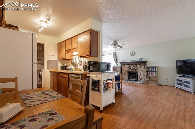 kitchen with ceiling fan, a fireplace, light hardwood / wood-style floors, and a textured ceiling