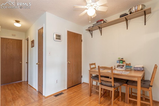 dining space featuring light wood-type flooring, a textured ceiling, and ceiling fan