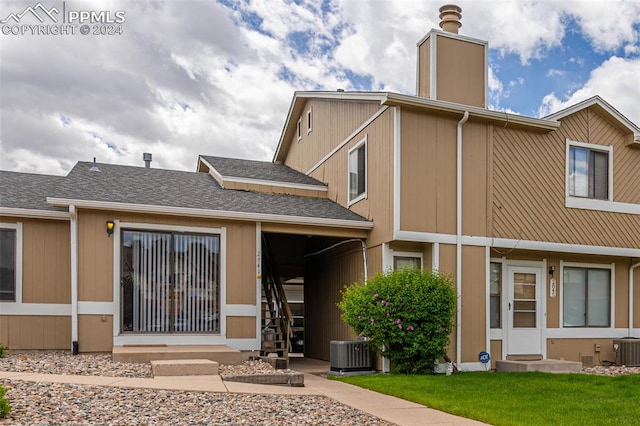 rear view of house with a yard and central AC