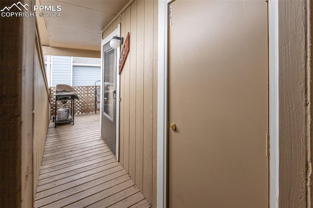 corridor with light hardwood / wood-style flooring and wooden walls