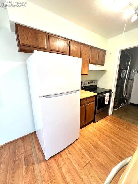 kitchen featuring stainless steel electric range oven, white refrigerator, and light wood-type flooring