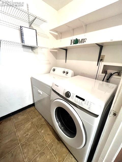 washroom with dark tile patterned flooring and washer and dryer