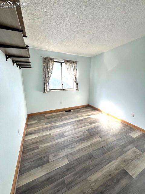 unfurnished room featuring a textured ceiling and wood-type flooring