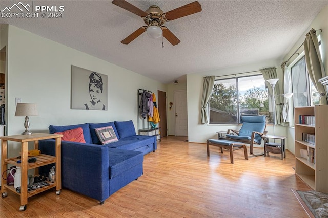 living room featuring ceiling fan, light hardwood / wood-style floors, and a textured ceiling