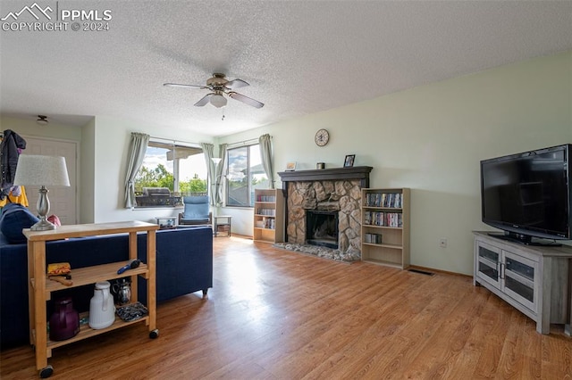 living room with a fireplace, a textured ceiling, wood-type flooring, and ceiling fan