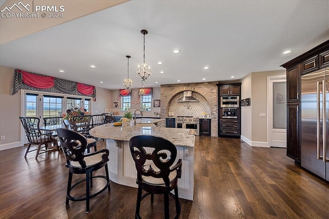 kitchen featuring dark wood-type flooring, high quality appliances, a center island with sink, and pendant lighting