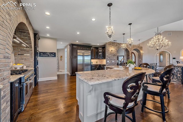 kitchen featuring hanging light fixtures, dark hardwood / wood-style flooring, dark brown cabinets, light stone counters, and high end appliances