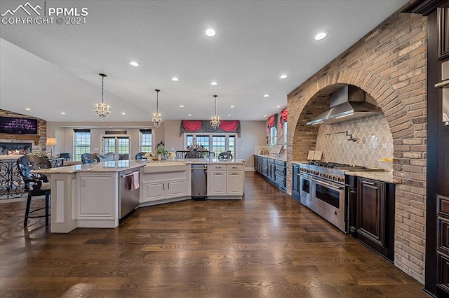 kitchen with dark wood-type flooring, appliances with stainless steel finishes, white cabinetry, and wall chimney exhaust hood