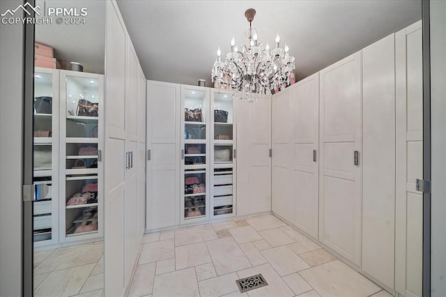 spacious closet featuring an inviting chandelier and light tile floors