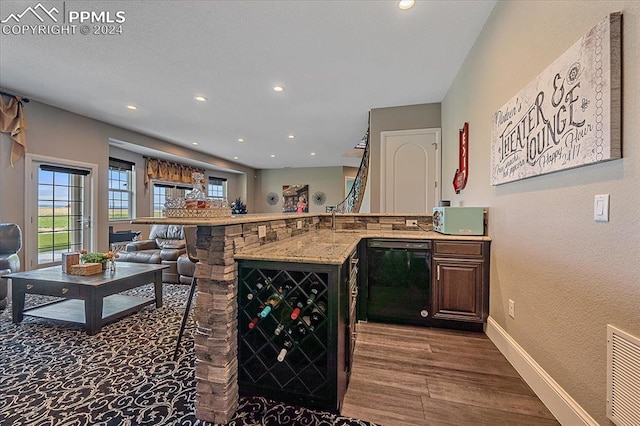 kitchen with hardwood / wood-style flooring, dishwasher, and light stone counters