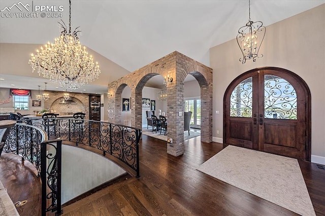 entrance foyer with a notable chandelier, vaulted ceiling, and dark wood-type flooring