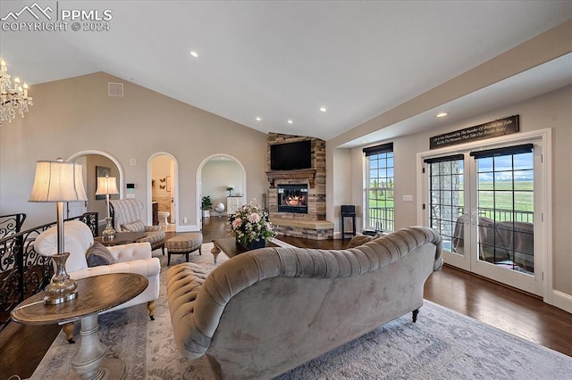 living room featuring french doors, a fireplace, wood-type flooring, an inviting chandelier, and lofted ceiling