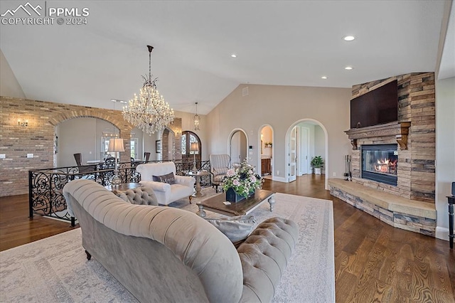 living room featuring dark hardwood / wood-style floors, a notable chandelier, vaulted ceiling, and a fireplace