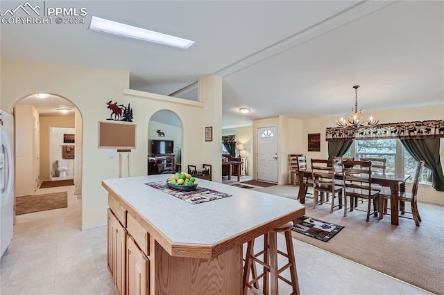 kitchen featuring a kitchen breakfast bar, a kitchen island, light tile floors, hanging light fixtures, and a chandelier