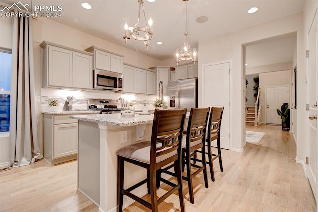 kitchen featuring light hardwood / wood-style flooring, tasteful backsplash, pendant lighting, and appliances with stainless steel finishes