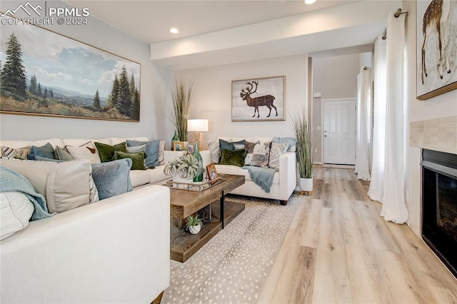 living room with light wood-type flooring and a tile fireplace