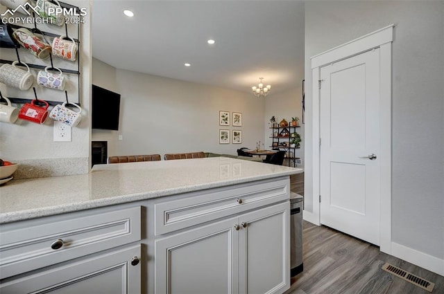 kitchen featuring wood-type flooring, kitchen peninsula, and a chandelier