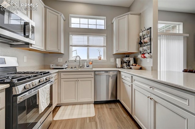 kitchen featuring stainless steel appliances, light hardwood / wood-style flooring, white cabinetry, and sink