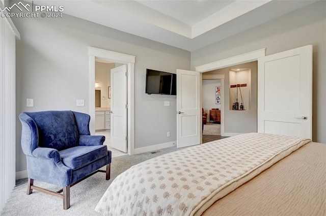 bedroom with ensuite bathroom and light colored carpet