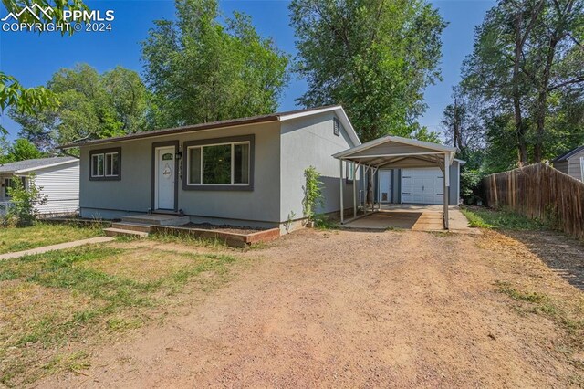 view of front of house with a garage, an outbuilding, a carport, and a front lawn