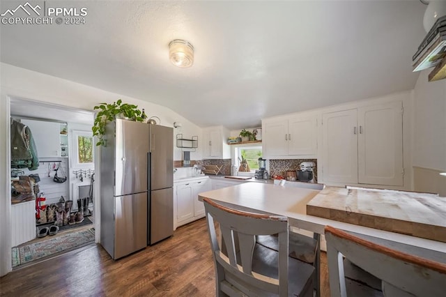 kitchen with backsplash, vaulted ceiling, stainless steel fridge, dark hardwood / wood-style flooring, and white cabinetry