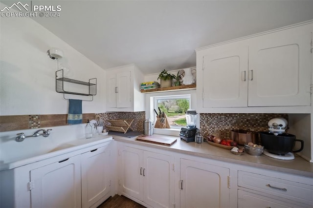 kitchen with white cabinets, backsplash, and lofted ceiling