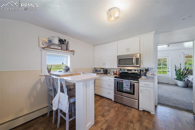 kitchen with kitchen peninsula, stainless steel appliances, a baseboard radiator, white cabinetry, and a breakfast bar area