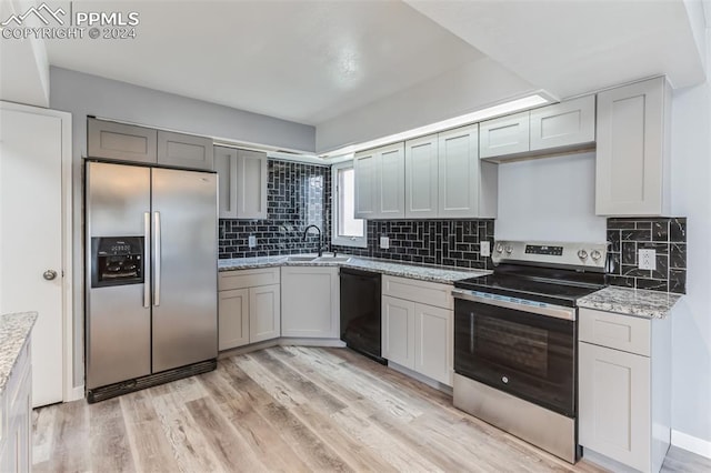 kitchen featuring stainless steel appliances, sink, backsplash, and light hardwood / wood-style flooring