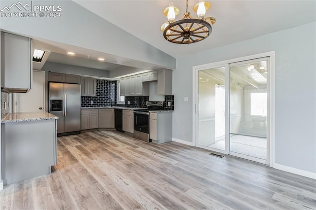 kitchen featuring light stone counters, decorative light fixtures, gray cabinets, stainless steel appliances, and decorative backsplash