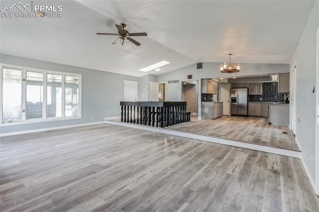 unfurnished living room with lofted ceiling, ceiling fan with notable chandelier, and light wood-type flooring