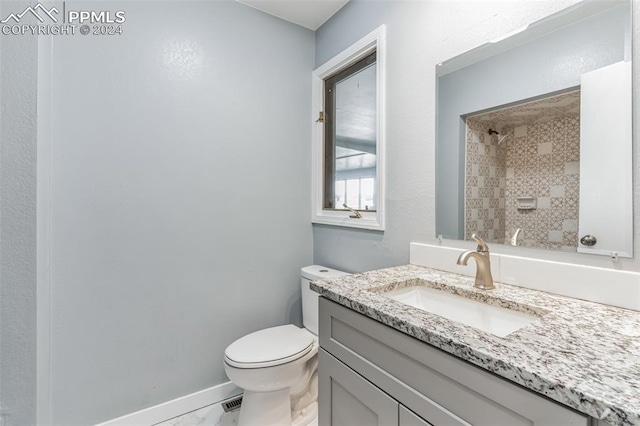 bathroom featuring vanity, toilet, and a tile shower