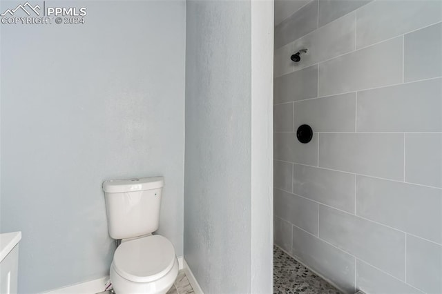 bathroom with tiled shower and toilet