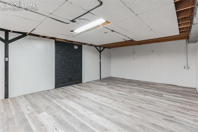 basement with a drop ceiling and light wood-type flooring