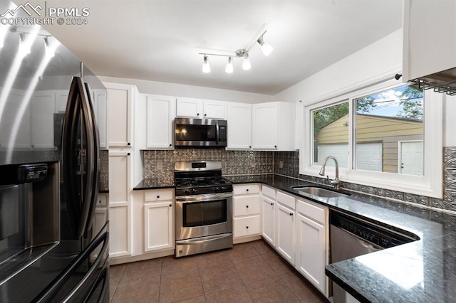 kitchen featuring dark tile patterned flooring, sink, decorative backsplash, appliances with stainless steel finishes, and white cabinetry