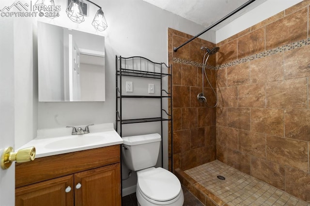 bathroom with tiled shower, vanity, and toilet