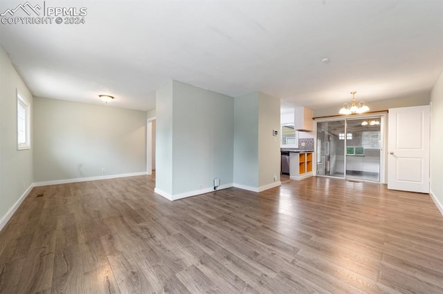 unfurnished living room with a chandelier and wood-type flooring