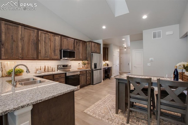 kitchen featuring dark brown cabinets, light stone countertops, sink, and appliances with stainless steel finishes