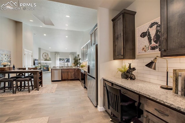 kitchen featuring backsplash, dark brown cabinetry, light stone counters, and stainless steel appliances