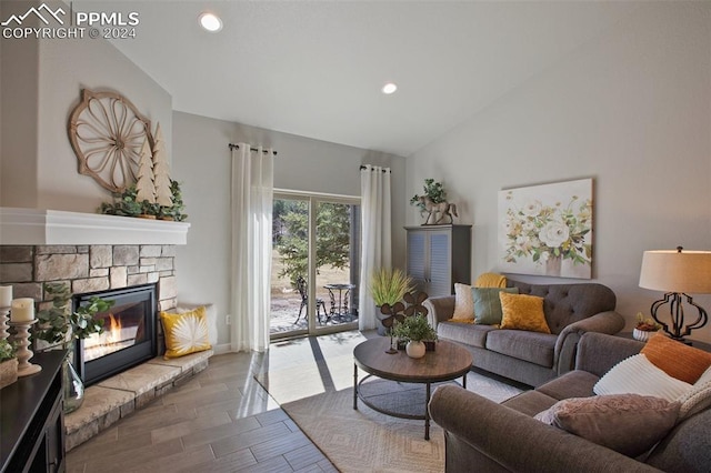 living room with a stone fireplace and lofted ceiling