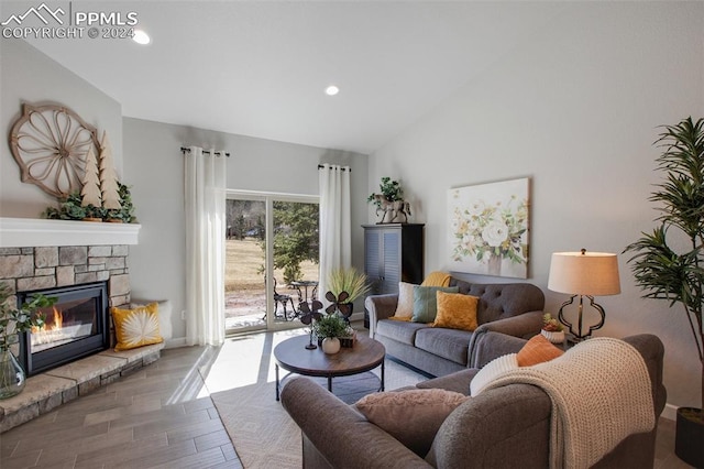 living room featuring a stone fireplace and lofted ceiling