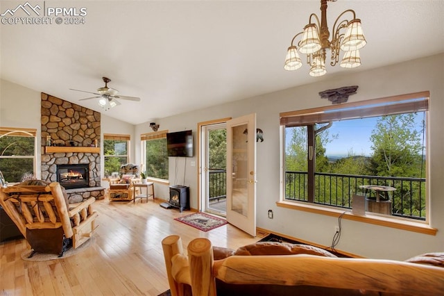 living room with vaulted ceiling, plenty of natural light, light hardwood / wood-style floors, and a wood stove