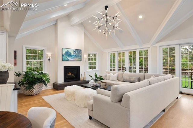 living room featuring beamed ceiling, light wood-type flooring, a healthy amount of sunlight, and a notable chandelier