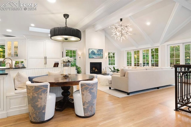 dining room featuring vaulted ceiling with beams, sink, an inviting chandelier, and light wood-type flooring