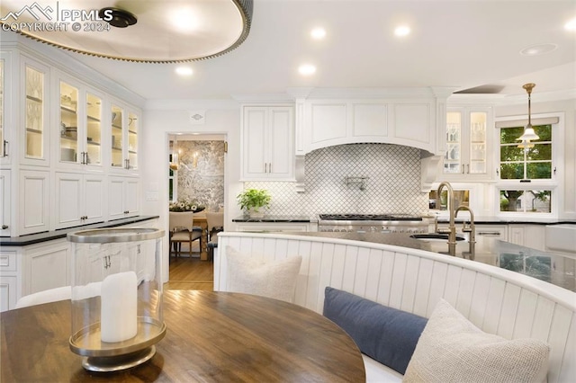 kitchen with sink, white cabinetry, hanging light fixtures, and tasteful backsplash